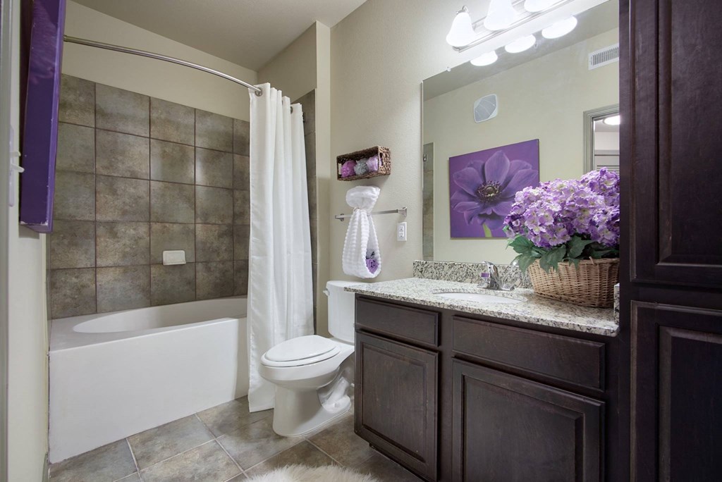 a bathroom with a white shower curtain and toilet next to a bathtub with a shower curtain