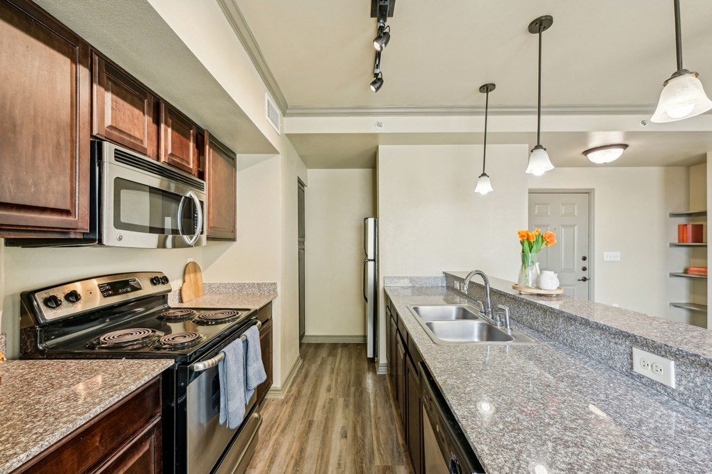 A kitchen with granite countertops and dark wood cabinets.
