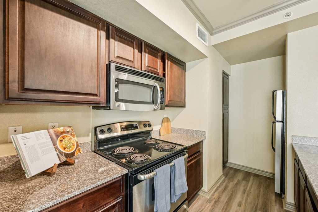 A kitchen with a stove, microwave, and refrigerator.