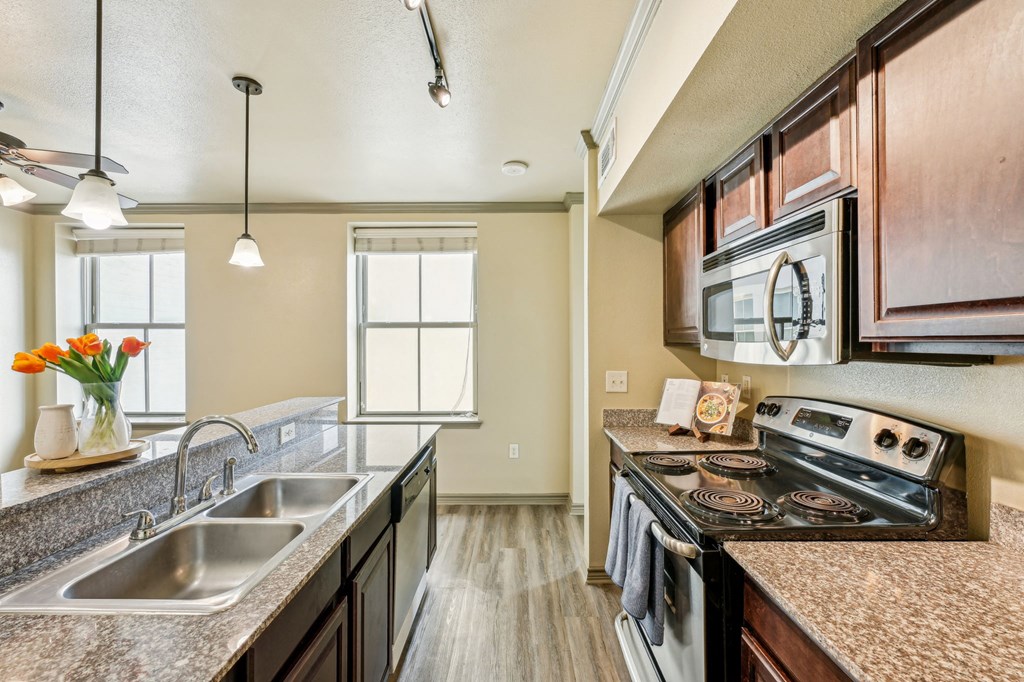 A kitchen with a stove, sink, and microwave.