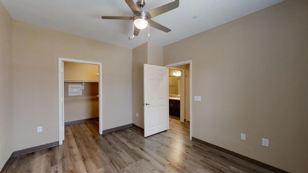 A room with a ceiling fan and wooden floors.