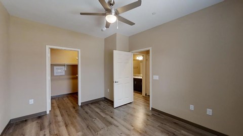 A room with a ceiling fan and wooden floors.