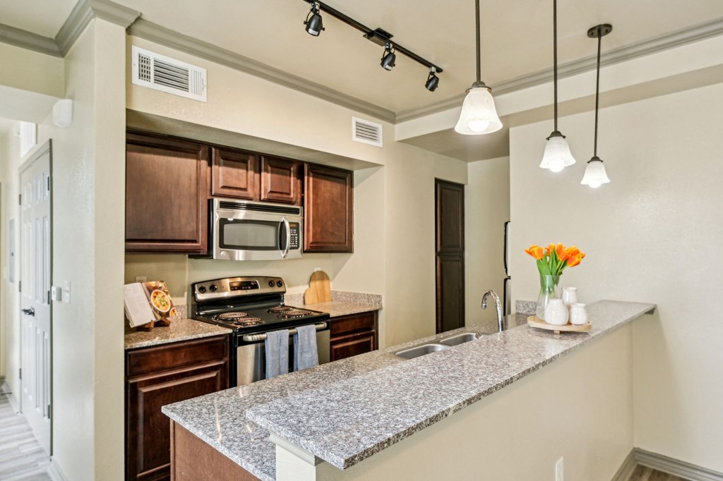 A kitchen with a granite counter top and a microwave above the stove.