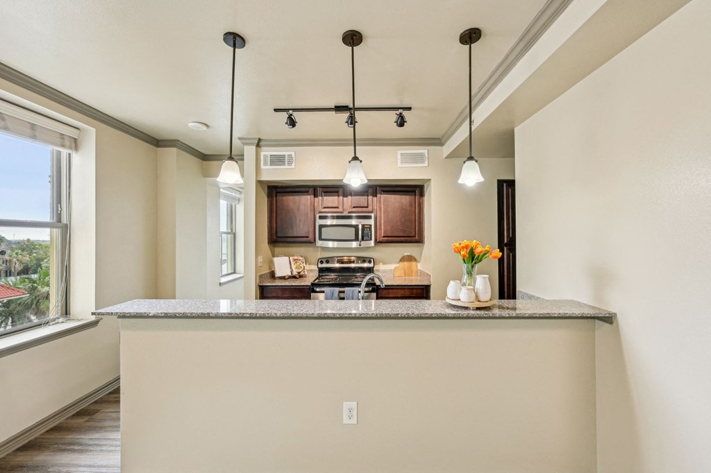 A kitchen with a large island and pendant lights.