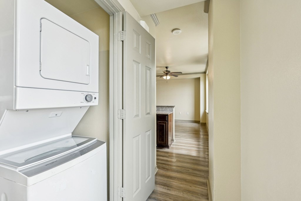 A white fridge and freezer in a room with a wooden floor and a ceiling fan.