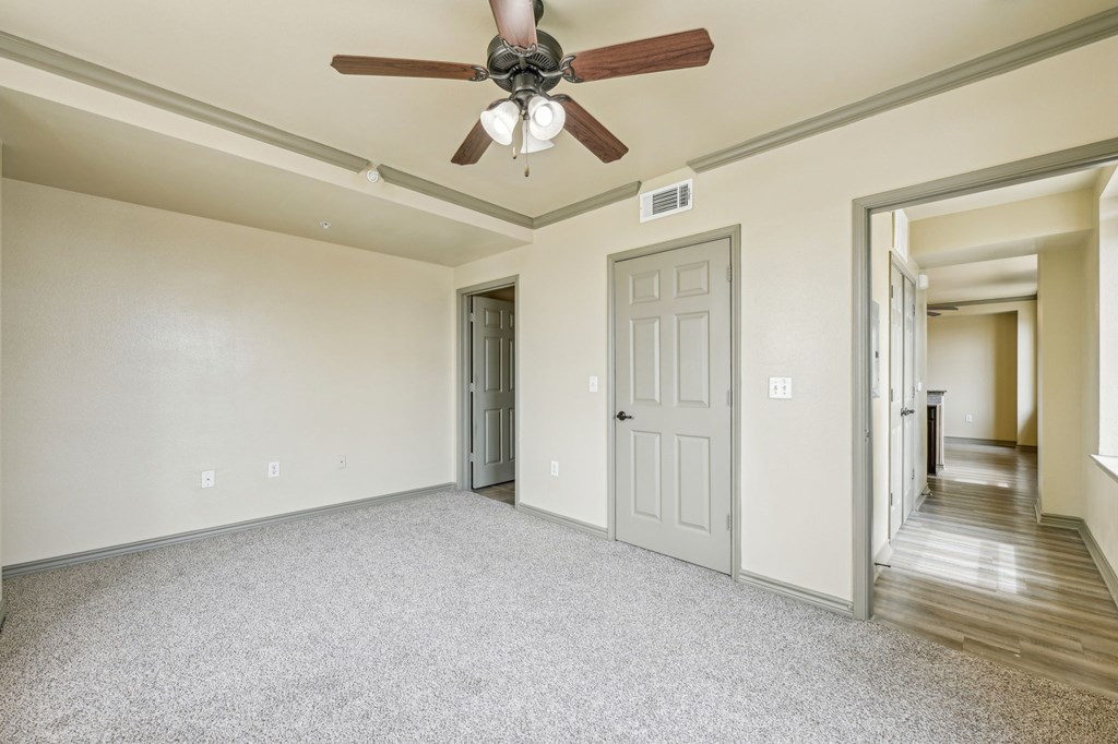 A room with a ceiling fan and two doors.