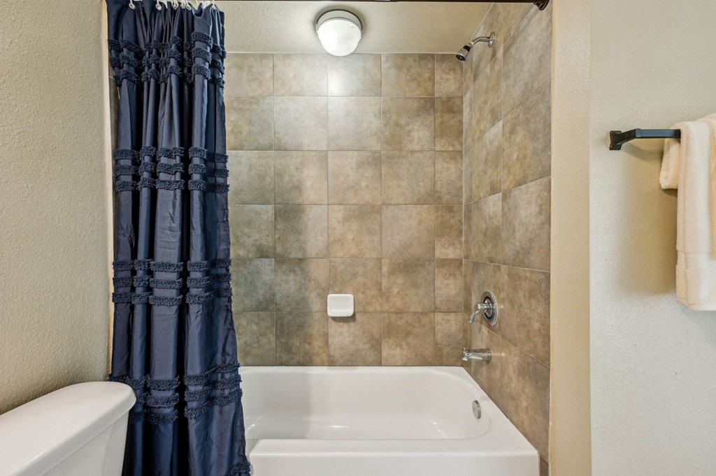 A white bathtub with a blue shower curtain in a bathroom.