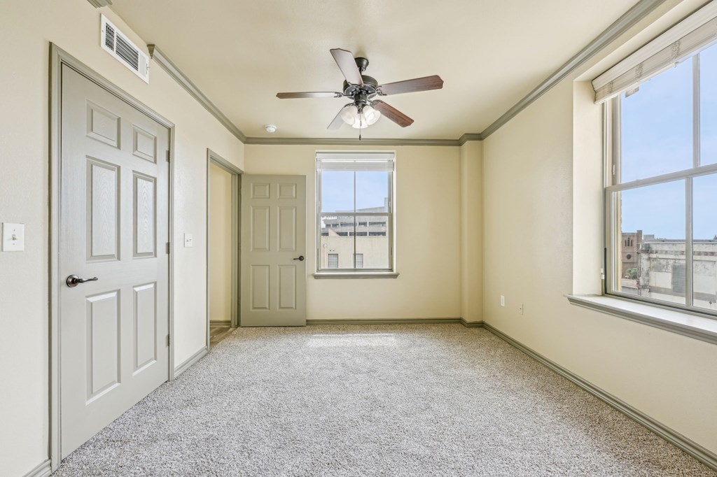 A room with a ceiling fan and a window overlooking a cityscape.