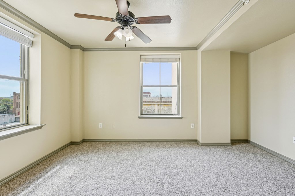A room with a ceiling fan and a window overlooking a cityscape.