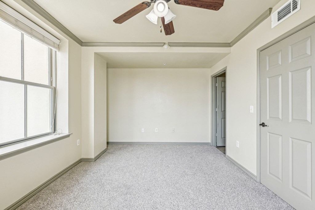 A room with a ceiling fan and a door.