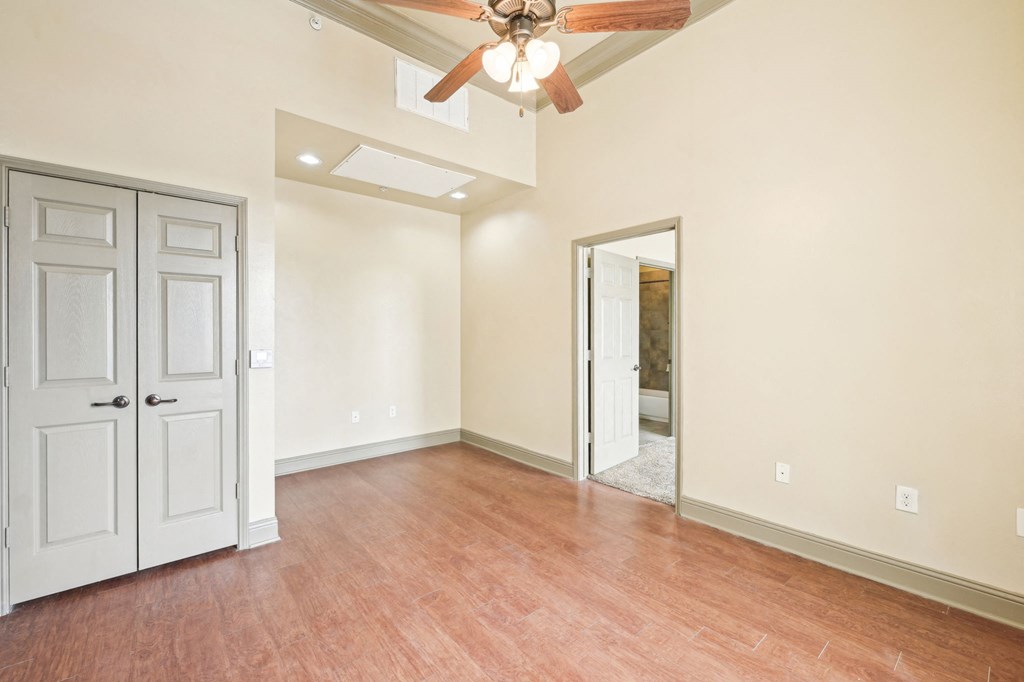 A room with a ceiling fan and wooden flooring.