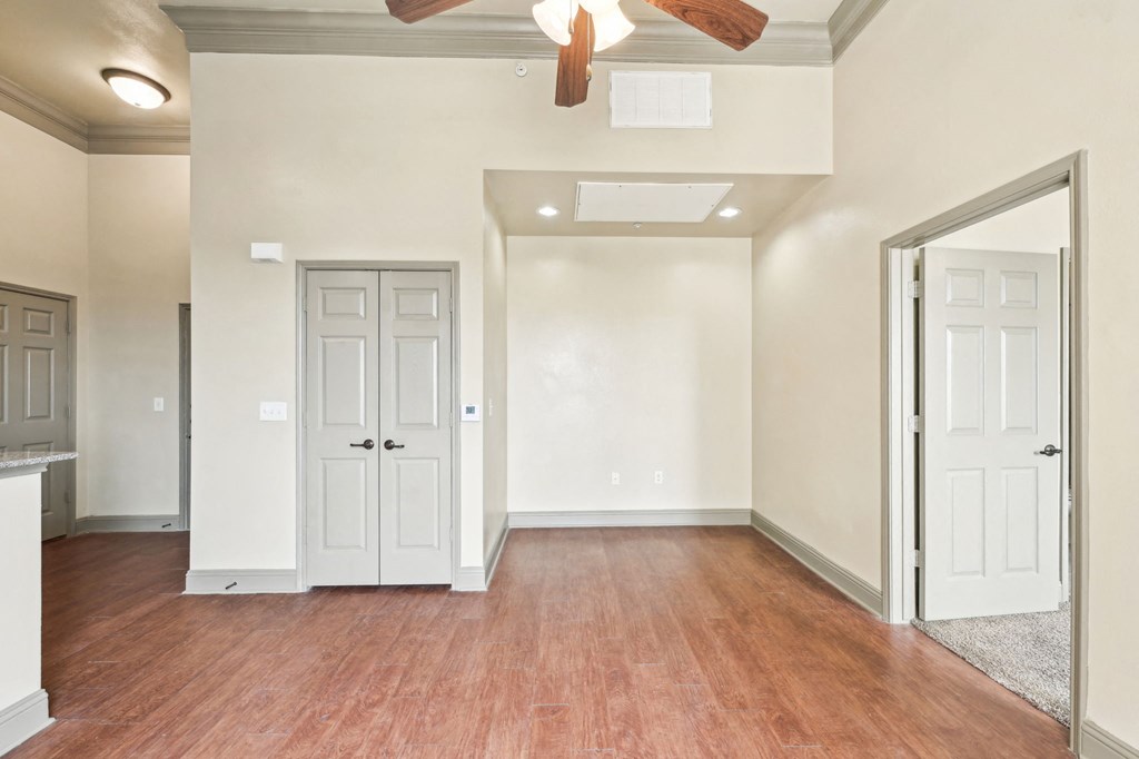 A room with a ceiling fan and wood flooring.