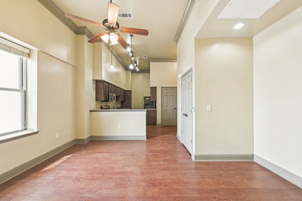A room with a ceiling fan and a brown floor.