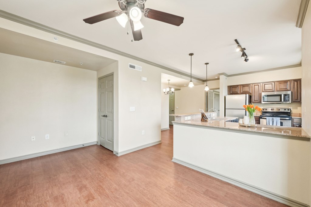 A room with a ceiling fan and a counter with a microwave.