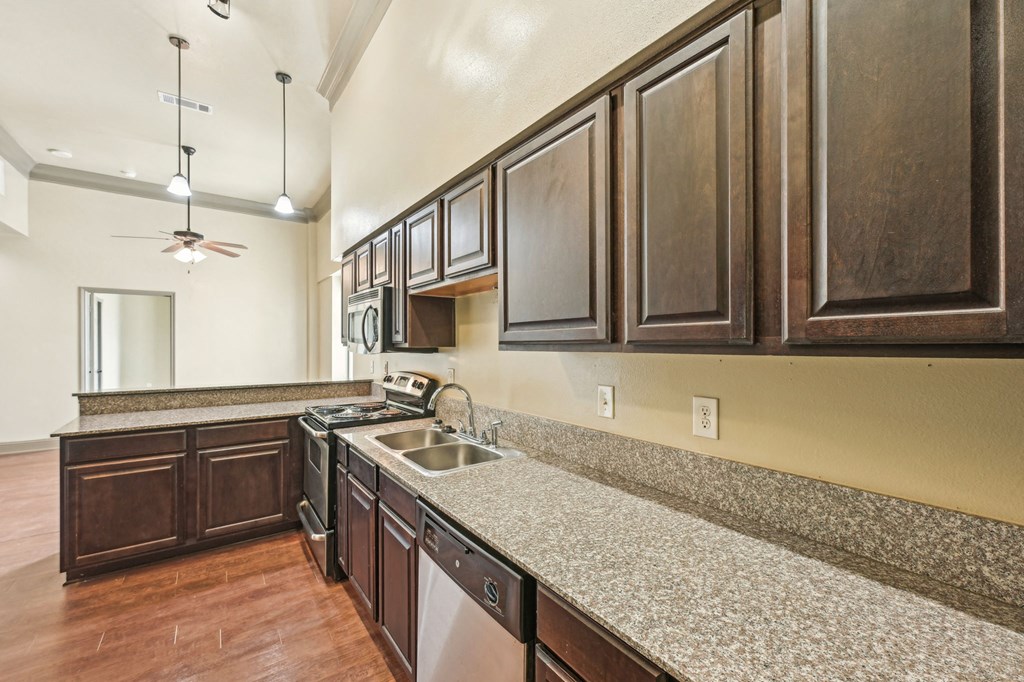 A kitchen with dark wood cabinets and a granite countertop.