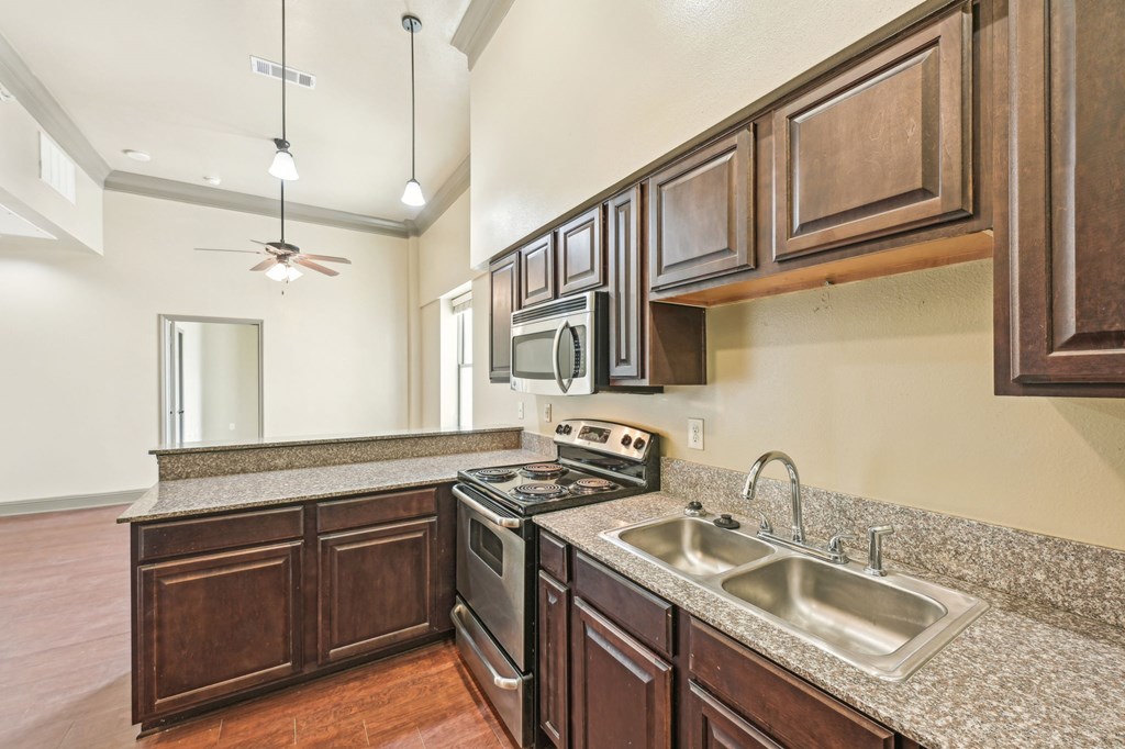A kitchen with brown cabinets and a granite countertop.