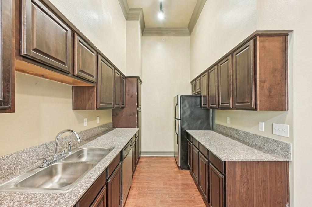A kitchen with brown cabinets and a granite counter top.