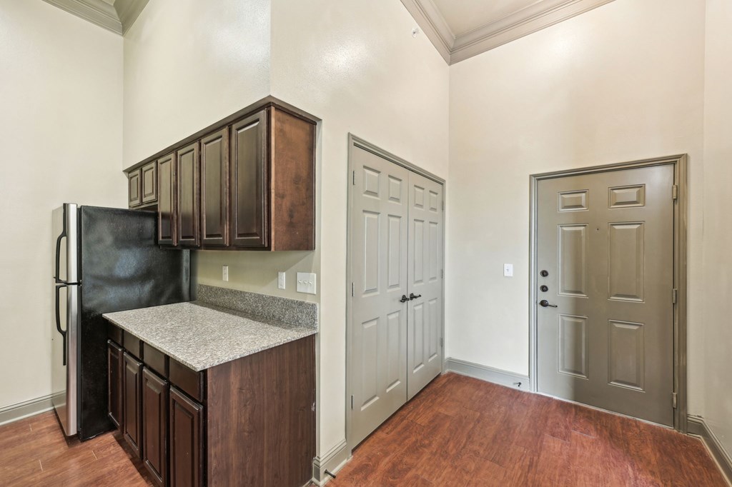 A kitchen with a black fridge and wooden cabinets.