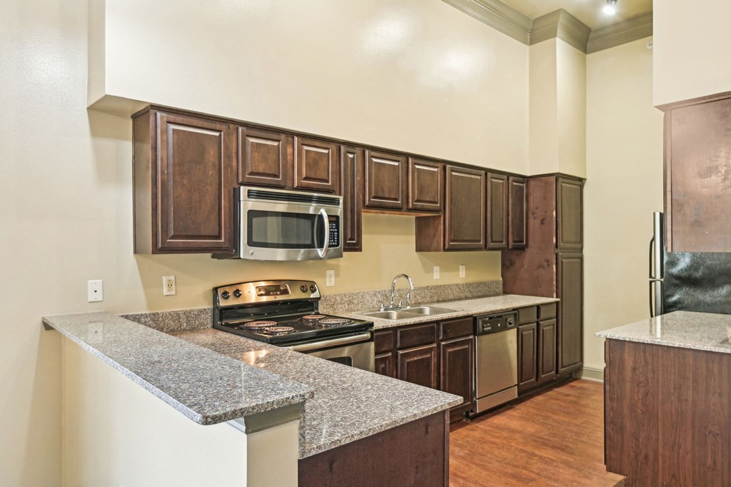 A kitchen with brown cabinets and granite countertops.