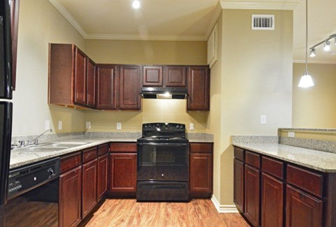 A kitchen with wooden cabinets and a black stove top oven.