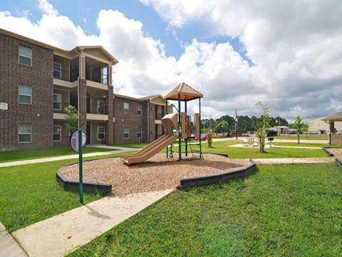 A playground with a slide and a building in the background.