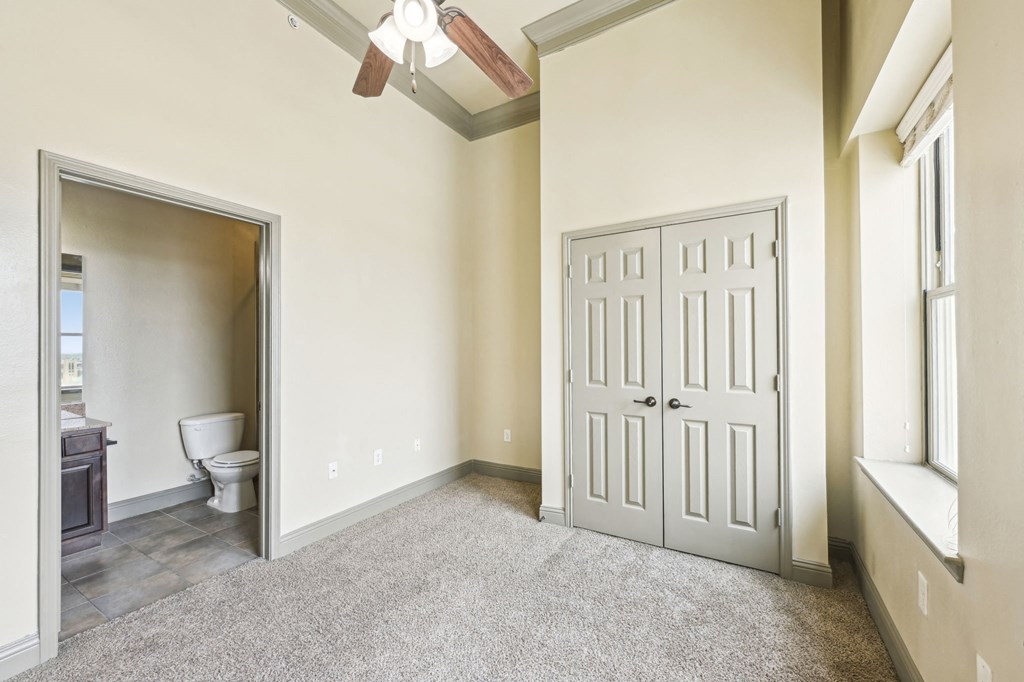 A room with a toilet, a fan, and a door.