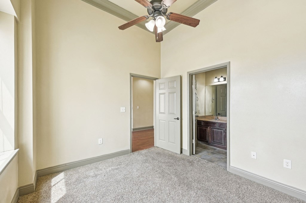 A room with a ceiling fan and a doorway leading to another room.