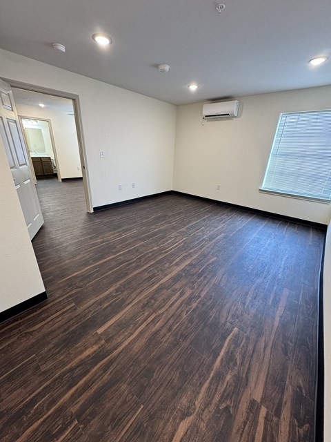 A room with wooden flooring and a window with blinds.