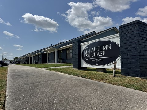 A sign for Autumn Chase stands in front of a building.