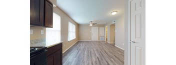 an empty living room and kitchen with a ceiling fan