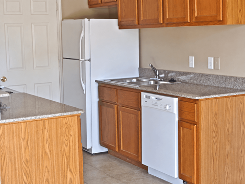 A white refrigerator stands in a kitchen with wooden cabinets.