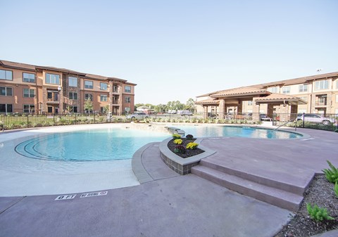 A swimming pool surrounded by a building and a flower bed.