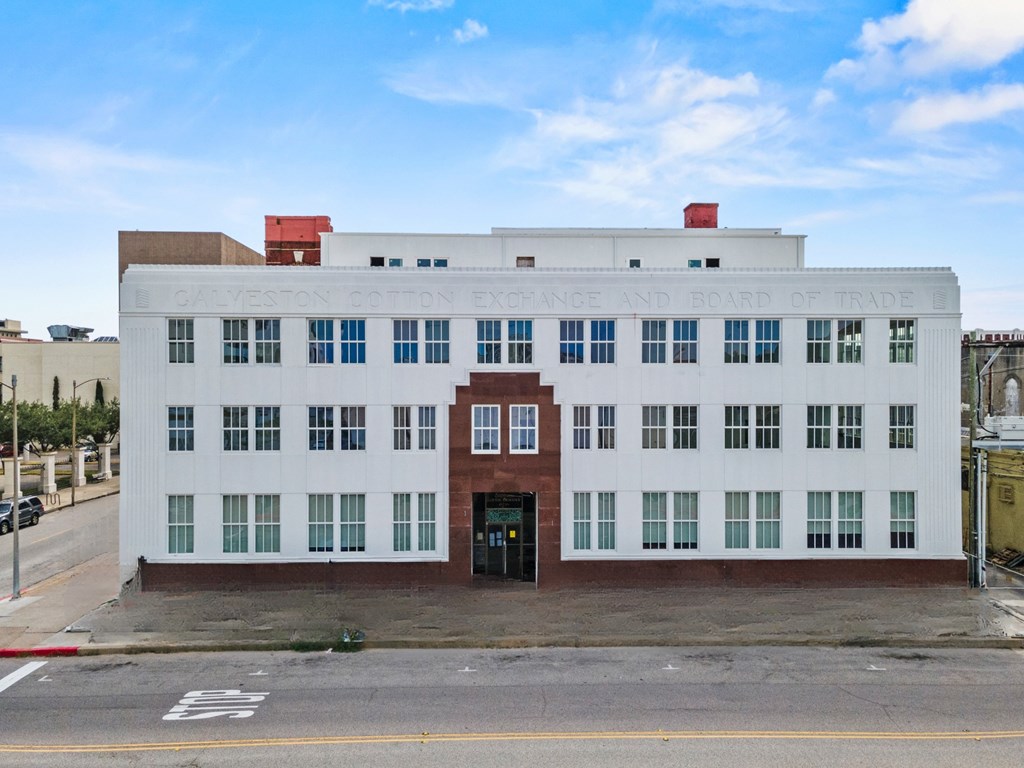 A white building with a red door and windows on the side.