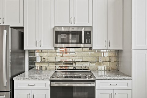 A kitchen with white cabinets and a stove top oven.