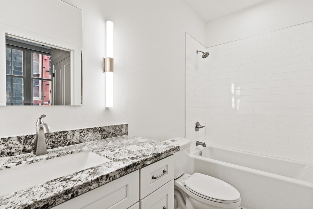 A modern bathroom with a marble countertop and a large mirror.