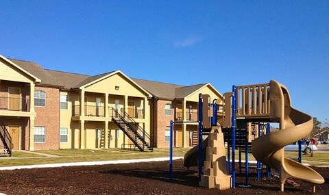 a playground with a slide in front of an apartment building