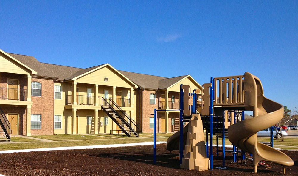 a playground with a slide in front of an apartment building