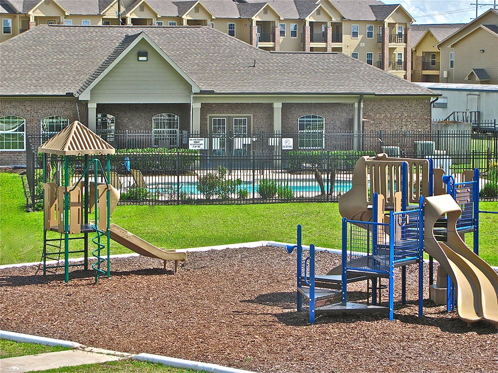 a playground with a slide and other toys in front of a house