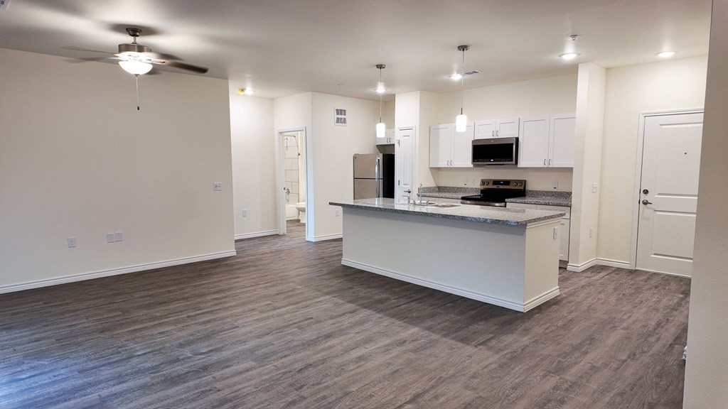 A spacious kitchen and living room with a ceiling fan and hardwood floors.