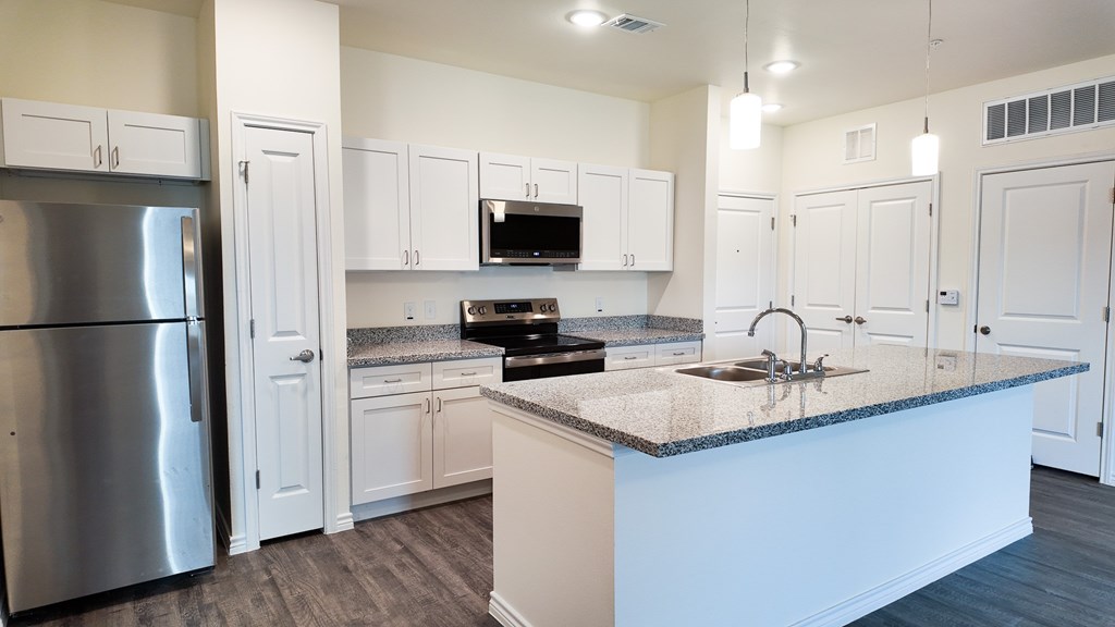 A kitchen with white cabinets and a granite countertop.