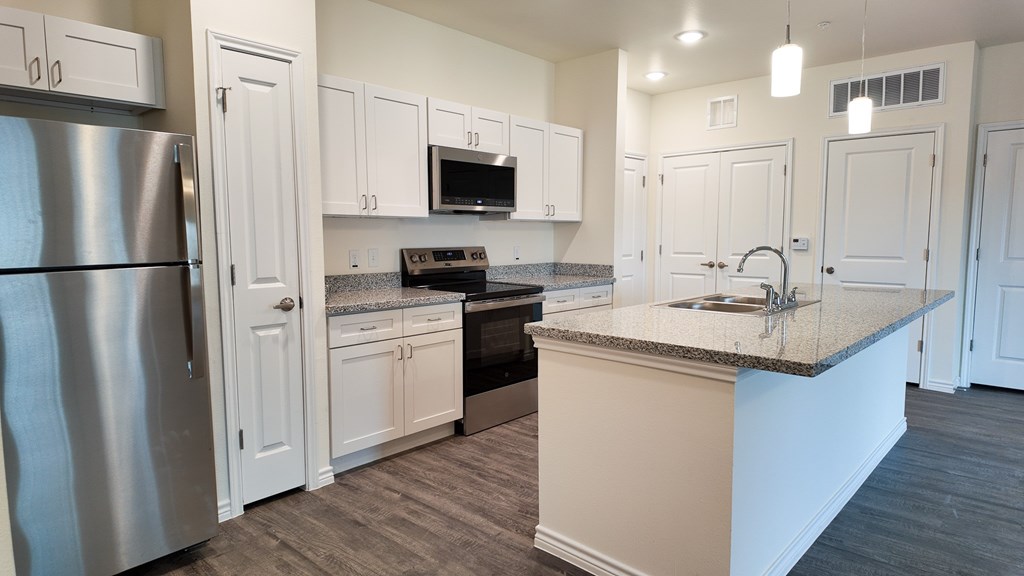 A kitchen with a stainless steel refrigerator and white cabinets.