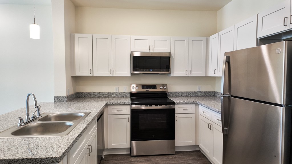 A kitchen with a stainless steel refrigerator, sink, oven, and cabinets.