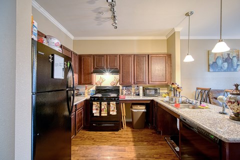A kitchen with a black refrigerator and wooden cabinets.