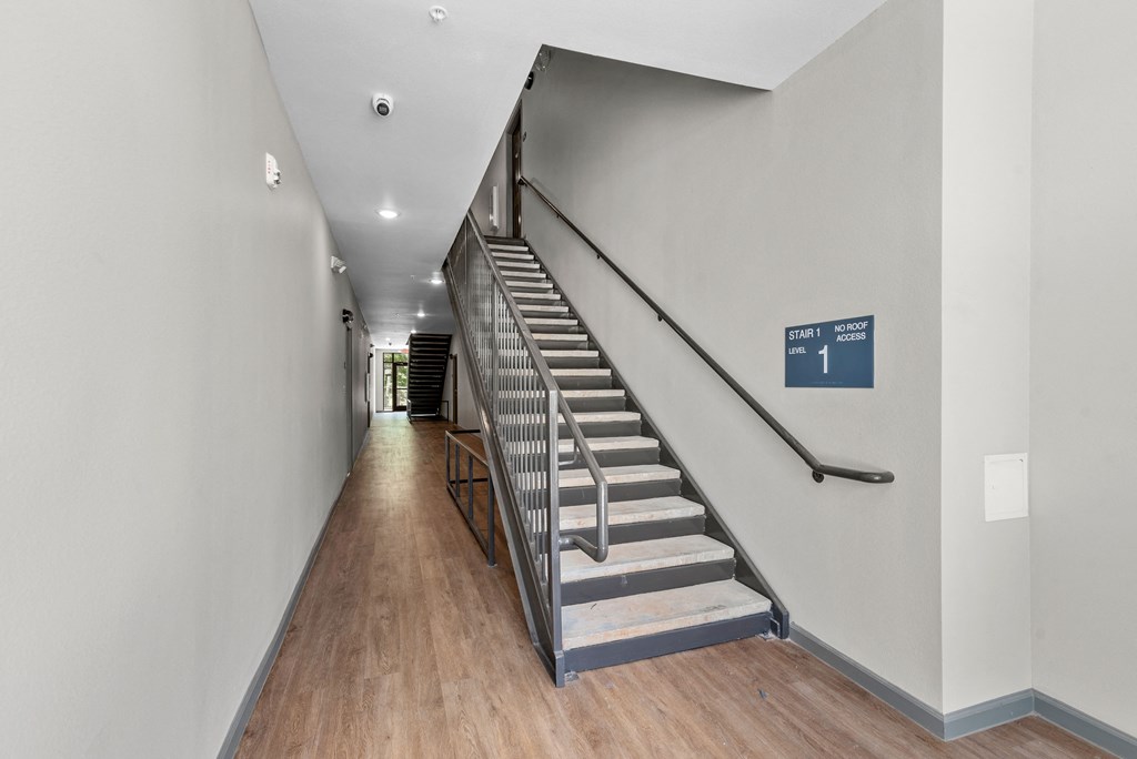 a set of stairs with a metal railing and a blue sign at the bottom of