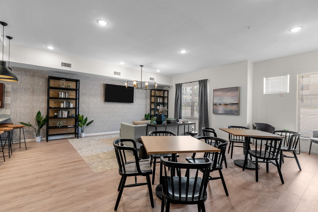 a community room with tables and chairs and a tv on the wall