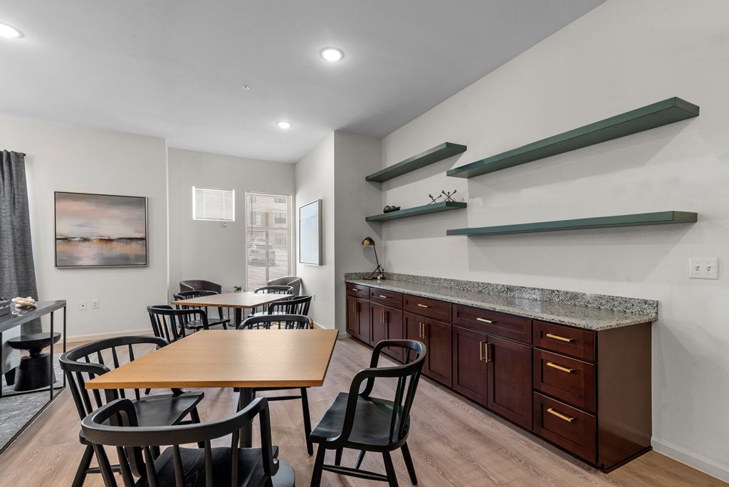 a dining room with tables and chairs and a kitchen with a counter and a table