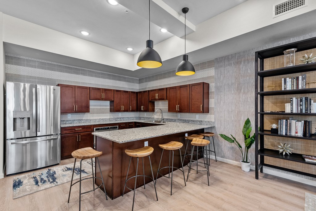 a kitchen with an island with bar stools and a stainless steel refrigerator