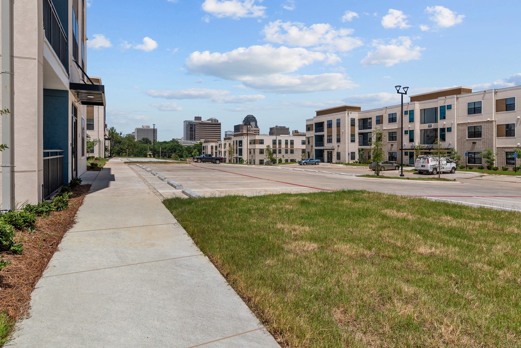 a view of a city street with buildings and a sidewalk