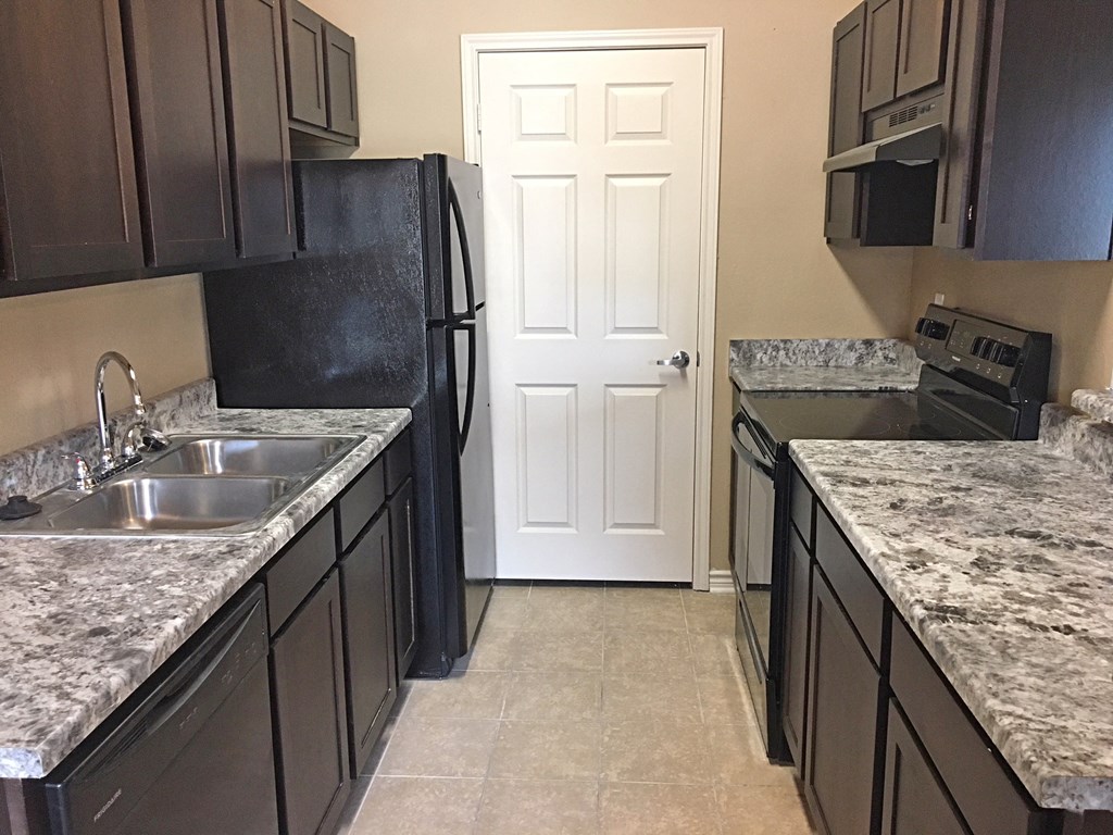 a kitchen with black cabinets and white marble countertops
