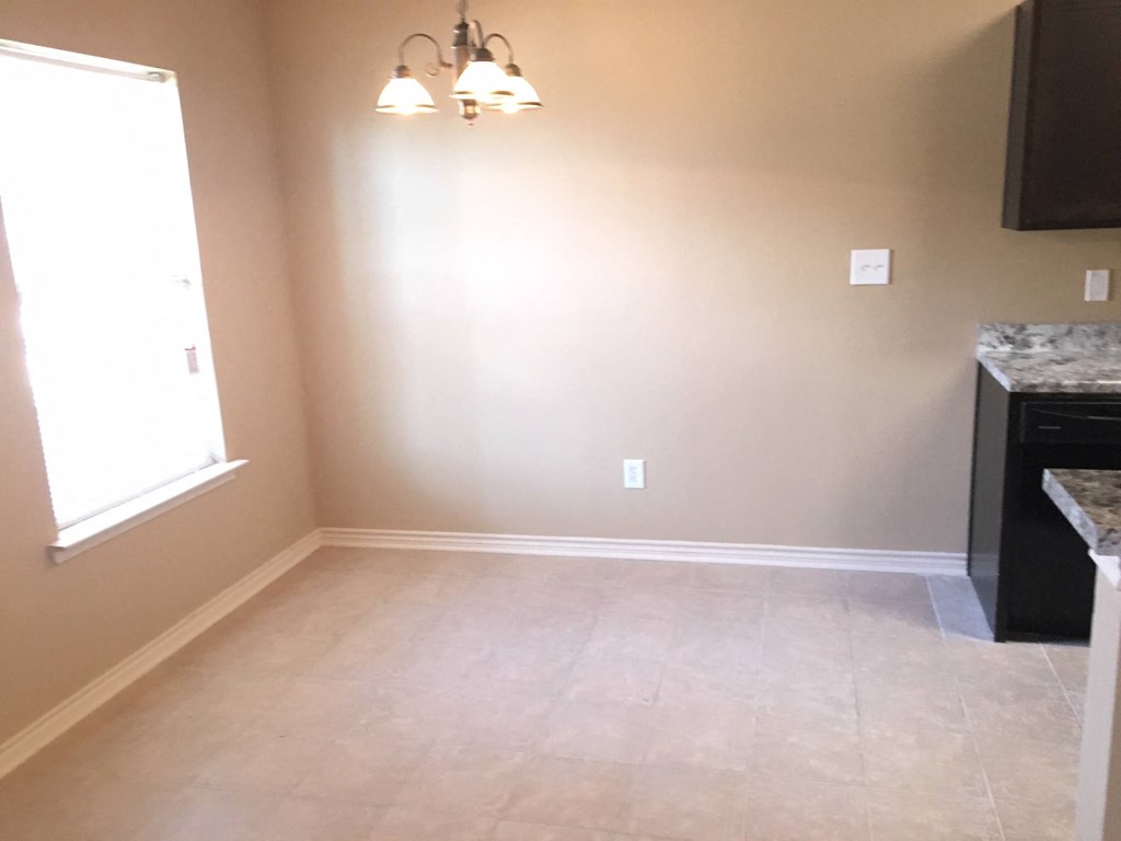 an empty room with a window and a chandelier